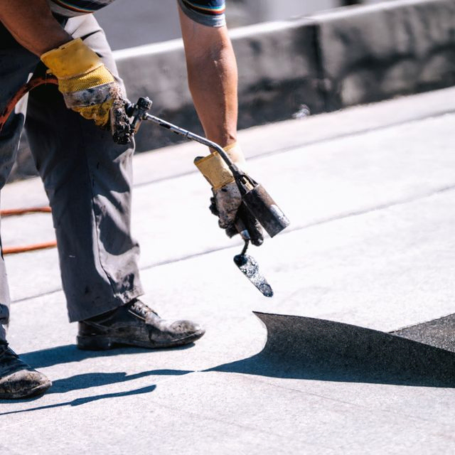 Trabajador impermeabilizando un tejado